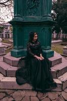 a ásia mulher vestido todos dentro Preto estava sentado dentro uma cemitério com uma muito assustador expressão enquanto atendendo a morte do dela irmão foto