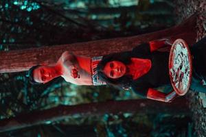 uma casal do serial assassinos ter corpos coberto dentro sangue e estão realizando uma satânico ritual dentro a meio do uma floresta foto
