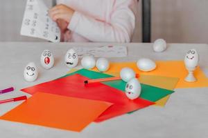 criança decora ovos com emocional adesivos às a mesa foto