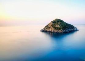 a ilha do bergeggi dentro a meio do a seda efeito mar em uma quieto verão manhã dentro ocidental ligúria 2021 foto