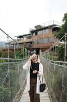 ásia mulher viajante em pé em uma suspenso ponte foto