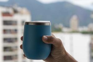 mão segurando uma caneca do água com uma Visão em a cidade fundo foto