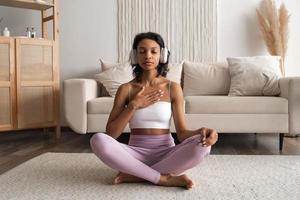 saudável Preto africano mulher às casa fazendo ioga, meditando e respiração dentro a manhã. bem estar saúde conceito foto