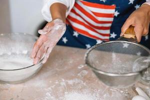 mãos de mulher peneirando farinha pela peneira. foco seletivo. foto
