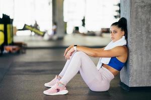 mulher jovem e saudável sentado relaxado após o treino no ginásio. foto