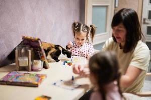 mãe e filhas decoração arte com brilhar decoração. Além disso gato com eles em mesa. foto