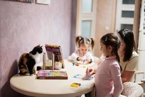 mãe e filhas decoração arte com brilhar decoração. Além disso gato com eles em mesa. foto