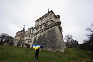 homem turista com a bandeira ucraniana nas mãos visita o castelo pidhirtsi, região de lviv, ucrânia. foto