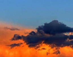 ansioso pôr do sol. cinzento e laranja nuvens dentro azul céu. foto