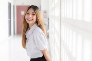 retrato do fofa tailandês aluna dentro universidade aluna uniforme. jovem ásia lindo menina em pé sorridente com confiança às universidade. foto