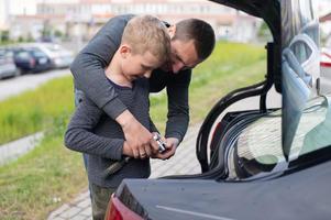 Papai ensina dele fofa filho para usar uma carro reparar ferramenta foto