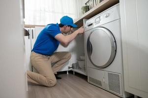 a ásia jovem técnico serviço homem vestindo azul uniforme verificação elétrico eletrodomésticos dentro casa foto