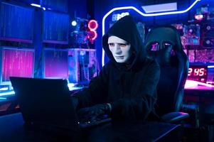 um hacker está usando um laptop para roubar dados durante a noite foto