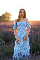 atraente delgado feliz menina dentro uma azul vestir dentro uma lavanda campo às pôr do sol. foto