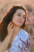 retrato do uma feliz mulher dentro uma azul vestir desfrutando uma ensolarado verão dia dentro uma lavanda campo. fresco ar, estilo de vida. foto