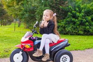 pequeno menina em uma elétrico motocicleta foto