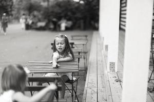 pequeno meninas sentado em ao ar livre jantar área foto