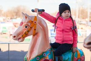 pequeno menina em uma carrossel foto