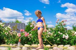 pequeno menina em a jardim com uma rosa foto