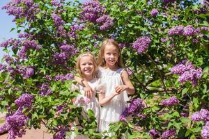 pequeno irmãs com flores dentro a jardim foto