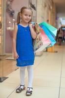 pequeno menina com compras bolsas foto