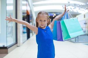pequeno menina com compras bolsas foto