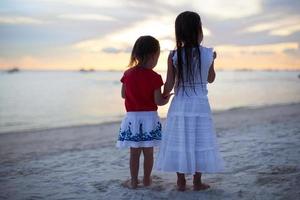 pequeno irmãs em a de praia foto