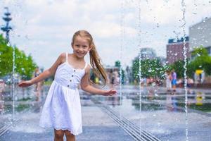 pequeno menina jogando em uma água fonte foto