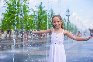 pequeno menina jogando em uma água fonte foto