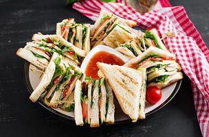 clube sanduíche com presunto, tomate, pepino, queijo, e Rúcula em Sombrio fundo. foto