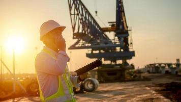 engenheiro falando em walkie-talkie e usando inteligente telefone para trabalhando às construção local foto