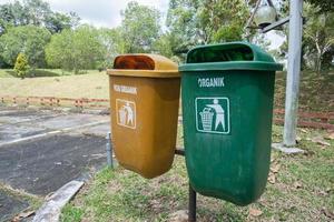 foco foco em a dois amarelo e verde Lixo latas, verde para reciclável desperdício, amarelo não reciclável Lixo dentro a lazer parque área, suave foco foto