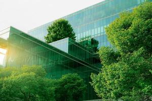 edifício verde sustentável. edifício ecologicamente correto. edifício de escritórios de vidro sustentável com árvore para reduzir o dióxido de carbono. escritório com ambiente verde. edifício corporativo reduzir o co2. vidro de segurança. foto