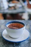 vapor quente cappuccino dentro uma branco cerâmico caneca com bokeh fundo foto
