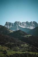 majestoso montanhas dentro a Alpes coberto com árvores e nuvens foto