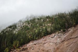 majestoso montanhas dentro a Alpes coberto com árvores e nuvens foto