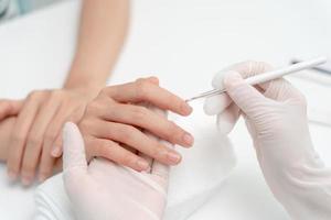 mulher recebe serviço de atendimento por manicure esteticista profissional no centro de spa. salão de beleza de unhas usa lixa de unha para tratamento de esmalte. manicure faz cliente de unha bonita. tratamento de spa para cuidados com o corpo foto