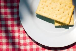 em topo do a biscoitos em a prato é uma xadrez toalha de mesa fundo. foto