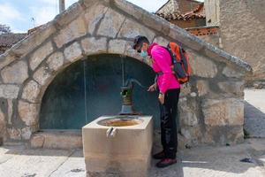 mulher com mochila e mascarar operativo a Antiguidade água fonte foto