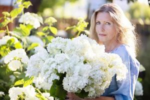 linda mulher idosa com um buquê de flores. mulher sorridente em seu jardim. foto