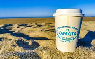 porto escondido Oaxaca México 2023 café para ir caneca em a de praia areia mar ondas. foto