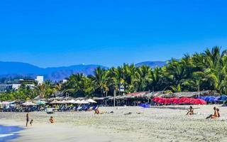 porto escondido Oaxaca México 2023 pessoas guarda-sóis Sol espreguiçadeiras de praia ondas Palmeiras zicatela México. foto