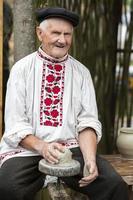 bielorrússia, a Vila do lyaskovichi. agosto 20, 2022. uma feriado do étnico culturas. a velho eslavo homem dentro uma bielorrusso linho bordado camisa esculpe Itens a partir de argila. étnico nacional trabalhos manuais. foto