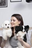 lindo menina às casa com uma cachorro. uma anfitriã com uma bichon e uma papillon senta em a cama. foto