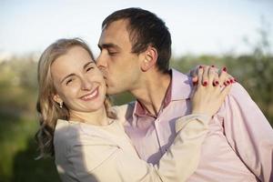 jovem casal feliz apaixonado ao ar livre. amar o homem e a mulher em uma caminhada em um parque florescente de primavera foto
