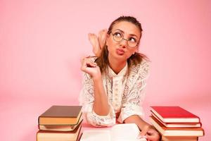 Rosa fundo, uma menina lê livros, uma livro amante, uma aluna mentiras em a chão entre uma ampla número do livros foto