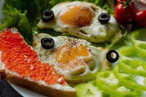 café da manhã, mexidos ovos em alface folhas, Próximo para fresco legumes e uma sanduíche com vermelho caviar foto