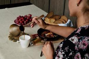 menina come café da manhã e derrama café a partir de uma turco foto