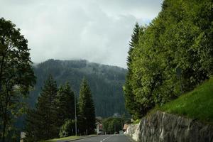 majestoso montanhas dentro a Alpes coberto com árvores e nuvens foto