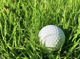 bola de golfe fechar na grama verde na bela paisagem borrada do campo de golfe com nascer do sol, hora do pôr do sol no esporte internacional background.concept que dependem de habilidades de precisão para relaxamento de saúde. foto